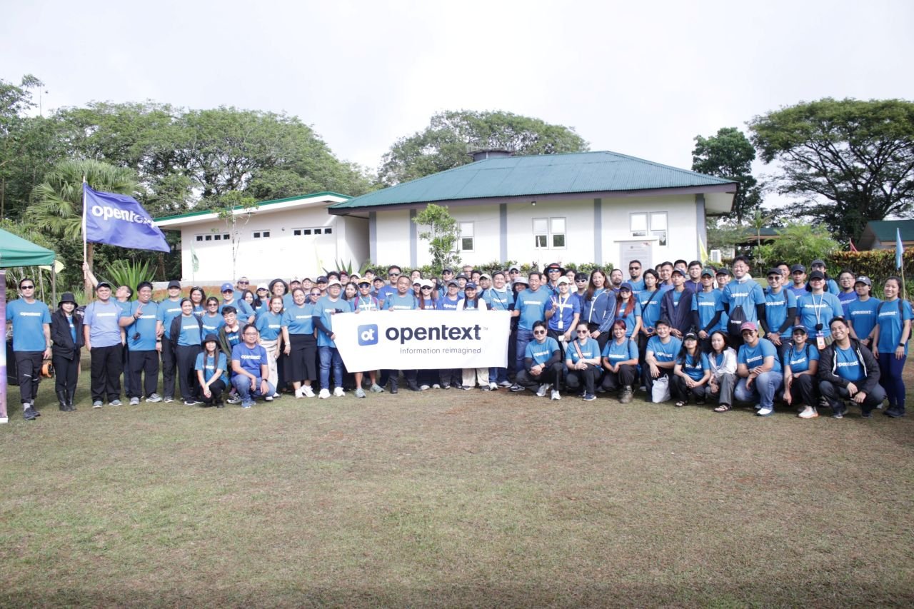 OpenText Philippines employees gathered behind an OpenText banner at a community outreach activity